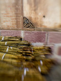 Bamboo Stacked in a Monastery near a Brick Wall, Qinghai, China Photographic Print by David Evans