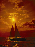A Passing Sailboat is Silhouetted against a Brilliant Orange Sunset Near Bermuda Photographic Print by Todd Gipstein