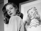 Actress Lauren Bacall Posing in Front of Portrait Drawing of Herself in Suite at the Gotham Hotel Reproduction photographique sur papier de qualité par Nina Leen