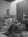 Architect Le Corbusier Sitting in Chair with Book in Hands, Glasses Perched on His Forehead Premium Photographic Print by Nina Leen