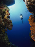 A Diver Swims Between Two Underwater Cliffs Photographic Print by Bill Curtsinger