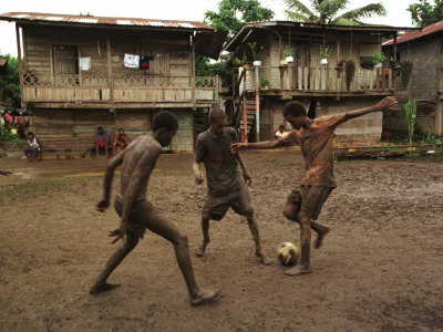 A Group of Panamanian Youths Slide Through the Mud During a Pick-Up Game of Soccer Photographic Print