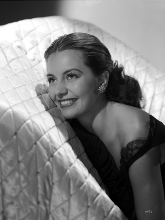 Cyd Charisse smiling in a White Couch wearing Black Sleeveless Dress and an Earrings Photo by  Movie Star News