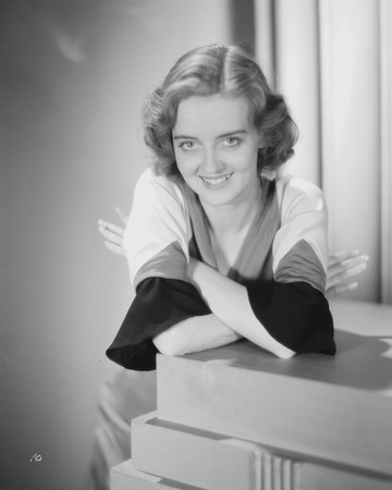 Bette Davis Leaning on a Table with Arms Crossed in Two Tone Long Sleeve Shirt and Velvet Skirt Photo by  Movie Star News