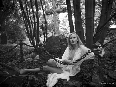 Veronica Carlson a white, chiffon, ruffled robe, while laying on the ground in the forest Photo by  Movie Star News