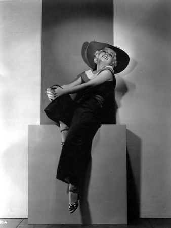 Muruel Evans on a Dark Top and Slacks with Hat sitting Portrait Photo by  Movie Star News