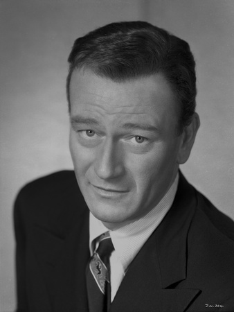 John Wayne Looking at the Camera, wearing a Black Suit and a Tie Photo by Gaston Longet