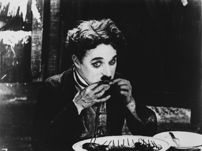 Charlie Chaplin Eating on Dining Table, wearing Black Suit Photo by  Movie Star News