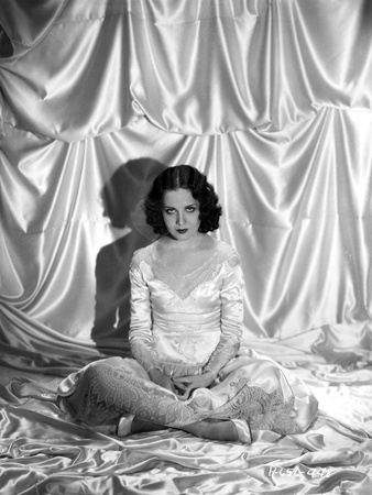 Mary Brian sitting in a White Shiny Dress in Photo by  Movie Star News