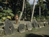 Man Stands Behind Large Stone Disks Treasured as Token Money Photographie par W. Robert Moore