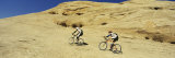 Two Men Mountain Bilking on Rocks, Slickrock Trail, Moab, Utah, USA Fotografie-Druck von Panoramic Images 
