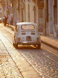 Fiat 500 Driving Down Cobbled Street, Noto, Sicily, Italy Photographic Print by John Miller