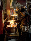 Woman Adding the Melting Yak Butter from Her Lamp to Those of the Temple, Bharkor, Tibet Photographic Print by Don Smith