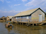 Man in Canoe Passing a House, Floating Fishing Village of Chong Kneas, Tonle Sap Lake, Cambodia Photographic Print by Jane Sweeney