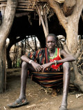 Karamojong Boy Sitting at Entrance to Hut, Uganda Photographie par Ariadne Van Zandbergen