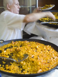 Man Serving Paella, with Noodle Paella in Foreground, Central, Valencia, Spain Photographic Print by Greg Elms