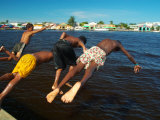 Young Boys Dive Off Marina at Bay of Belize with City in Background, Belize City, Belize Fotografie-Druck von Anthony Plummer