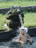 Boy Under a Water Spout, Watertemple, Bali, Indonesia Photographic Print by Gavin Hellier