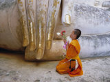 Novice Buddhist Monk Kneeling Beneath the Phra Atchana Buddha Statue, Sukhothai Province, Thailand Fotografisk tryk af Gavin Hellier