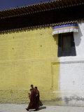 Buddhist Monks Walk Next to a Yellow and White Building, Qinghai, China Photographie par David Evans