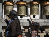 Buddhist Woman and Child Spin Brass Prayer Wheels, Qinghai, China Photographie par David Evans