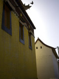 Bird Lands on the Edge of a Monastery Roof Seen against a Blue Sky, Qinghai, China Photographic Print by David Evans