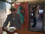 Man in Sunglasses Eats Soup in a Tent at a Nomadic Market, Qinghai, China Photographie par David Evans