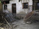 Rusty Satellite Dish and a Rickshaw Cart and Trash Outside a House, Qinghai, China Photographic Print by David Evans