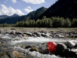 Red Paper Lantern Washed Up against Rocks in a River, Qinghai, China Photographie par David Evans