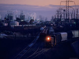 Trains Surrounded by Industrial Plants Photographic Print by Kenneth Garrett