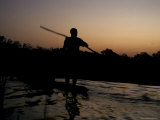 Village Tribesman Poles a Mekoro Through a Wetland Swamp at Sunset Photographie par Jason Edwards