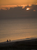 Sun Sets over Atlantic Ocean as 2 People Stroll Down the Beach Photographie par David Evans