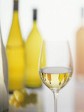 A Glass of White Wine and Wine Bottles in Background Photographic Print by Ulrike Koeb A Glass of White Wine and Wine Bottles in Background Photographic Print by Ulrike Koeb