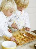Two Children Brushing Biscuits with Glace Icing Photographic Print by Renate Forster