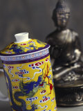 Decorated Teacup with Lid in Front of Statue of Buddha Fotografisk trykk av Dr. Martin Baumgärtner Decorated Teacup with Lid in Front of Statue of Buddha Fotografisk trykk av Dr. Martin Baumgärtner