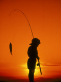 Silhouette d'un garçon pêchant au soleil couchant Photographie par Dean Berry