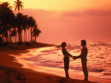 Silhouetted couple standing on a tropical beach Photographic Print by Wallace Garrison