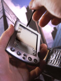 Main tenant un Palm Pilot M500 avec un téléphone portable Photographie par Eric Kamp