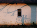 Shadow on a Wall of a Man Holding a Bicycle Photographic Print by Chris Johns