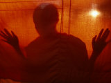 A Buddhist Monk is Silhouetted Behind a Hanging Curtain Lámina fotográfica por Paul Chesley