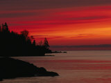 A Bright Red Sky over Lake Superior at Dawn with Silhouettes of the Rocky Coast Photographic Print by Maria Stenzel