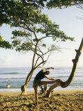 A Woman Stretches Her Body on a Small Tree at a Sandy Beach Fotografisk trykk av Skip Brown