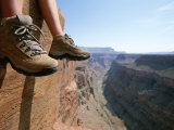 The Boot-Shod Feet of a Hiker Dangle over the Side of a Cliff Photographic Print by John Burcham