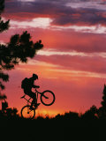 Silhouetted Biker Pulls a Wheelie at Twilight Photographic Print by David Edwards
