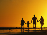 A Family Holding Hands is Silhouetted against the Setting Sun Fotografie-Druck von Rich Reid