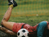 A Soccer Player Lands in the Mud in an Attempt to Field the Ball Photographie par Dugald Bremner