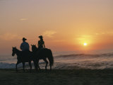 Two People on Horseback Ride Along an Ocean Shoreline at Sunset Photographic Print by Roy Toft