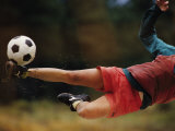 A Man Bends Sideways as He Kicks a Soccerball Photographic Print by Dugald Bremner