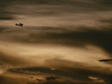 A Small Airplane Flies Through a Cloudy Sky over Key West, Florida Photographic Print by Raul Touzon