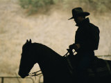 A Silhouette of a Rancher Riding a Horse Photographie par Dugald Bremner